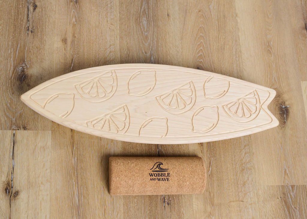 Wooden surfboard-shaped board with lemon designs on a wooden surface, featuring the Wobble and Wave brand. Great for core strength, coordination, and doubles as stylish home decor.