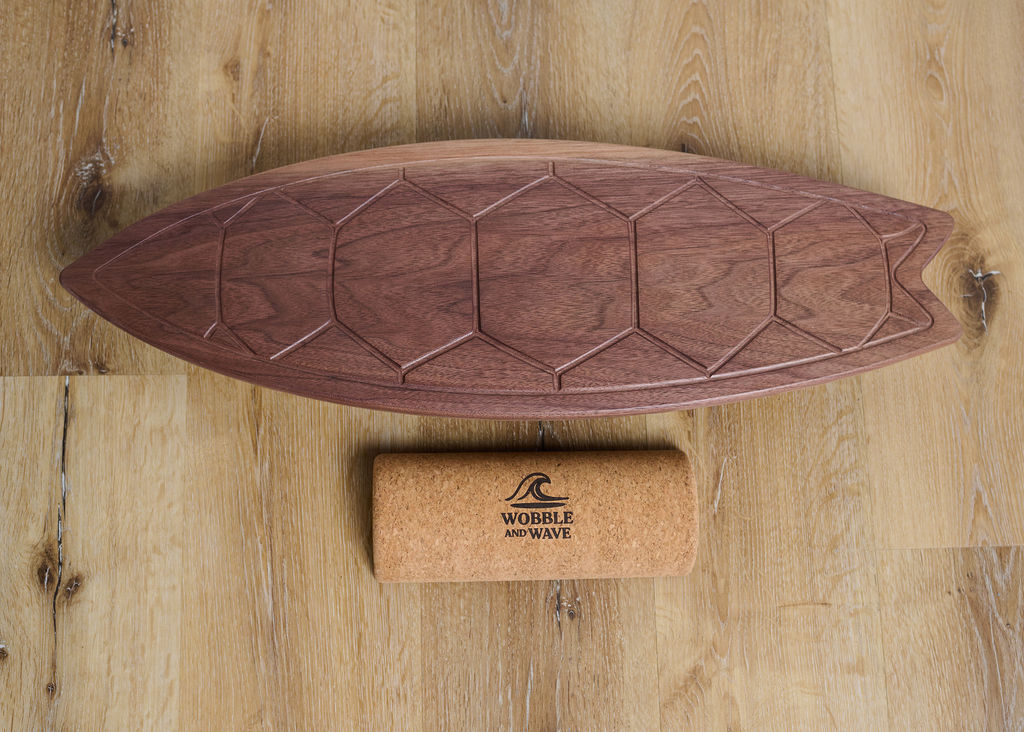 Wooden balance board with cork block on a wooden surface, featuring 'Wobble and Wave' branding. Premium walnut balance board engraved with a turtle shell pattern. Combines balance training, coordination play, and unique home style.