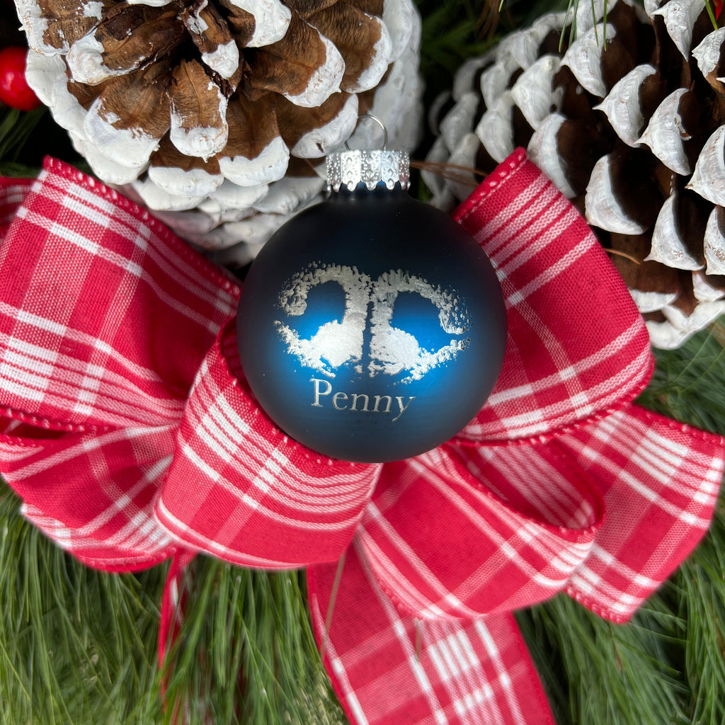 Christmas ornament with red plaid bow and pine cones on a green background