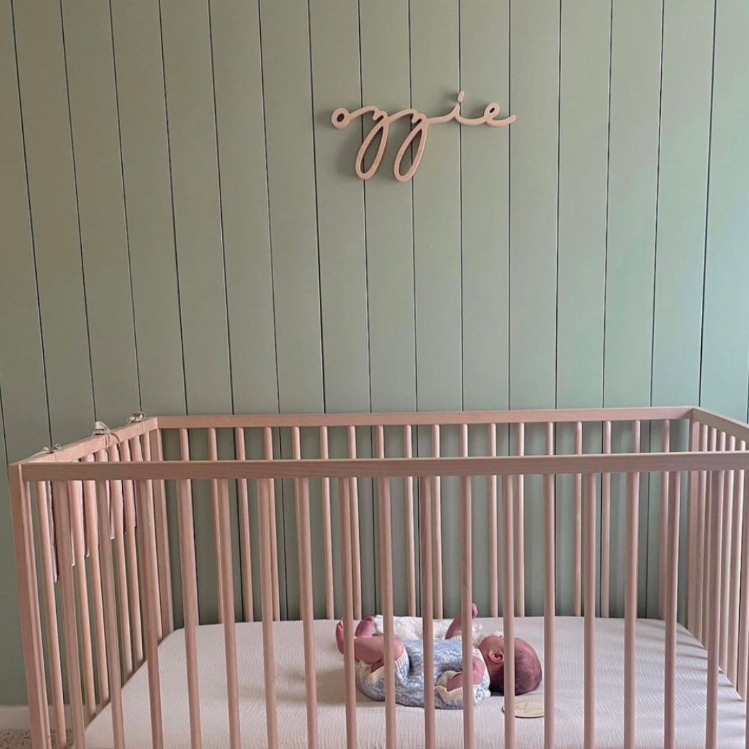 wooden name sign above crib in green room