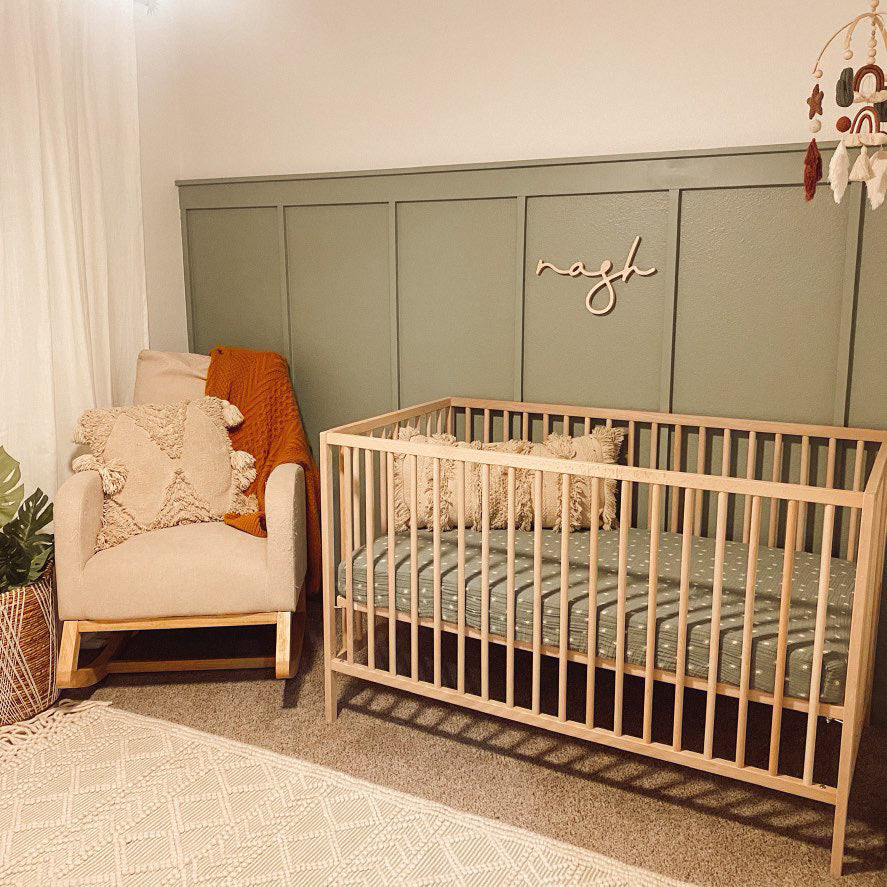 green boy nursery with wooden name sign above crib