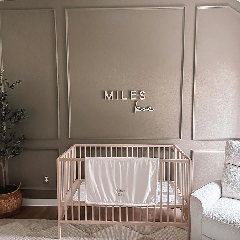 boy nursery with wooden name sign above crib