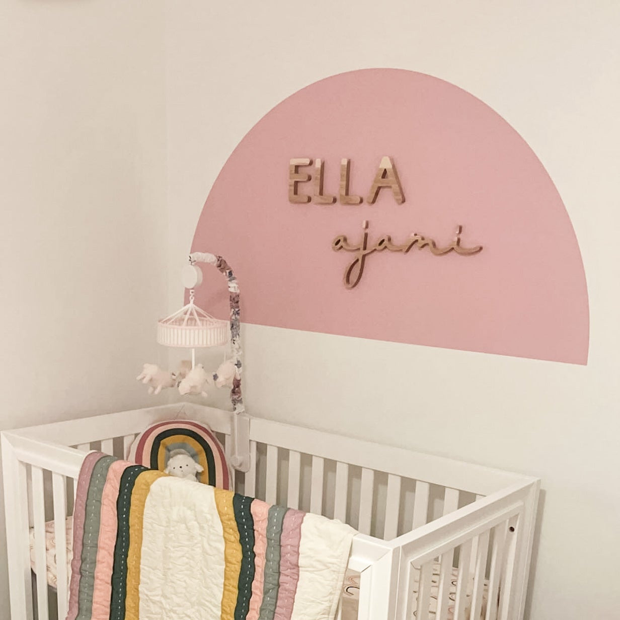 pink arch in girl nursery with wooden name sign 