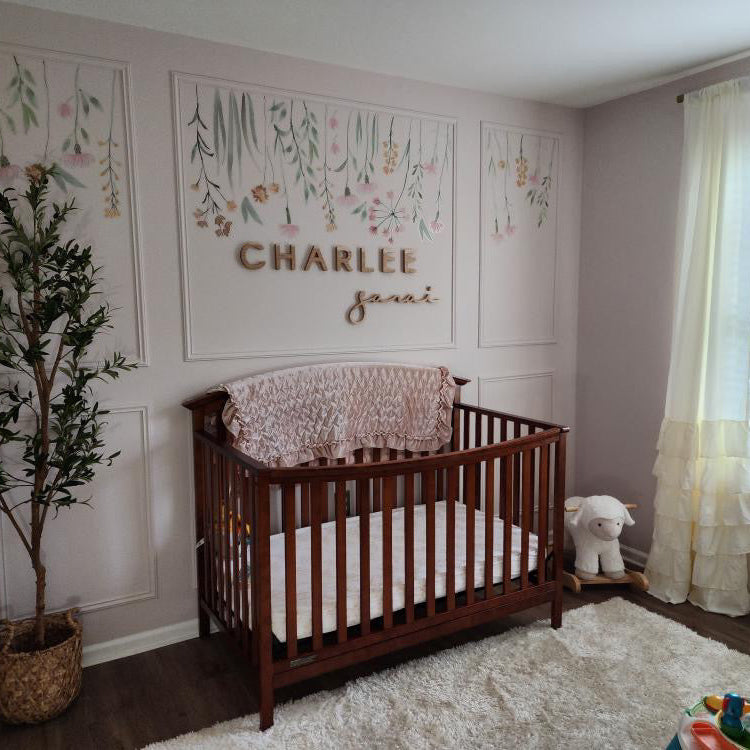 girl nursery with wooden name sign above crib