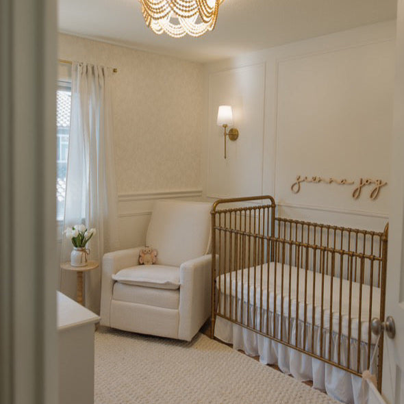 girl nursery with wooden name sign above crib