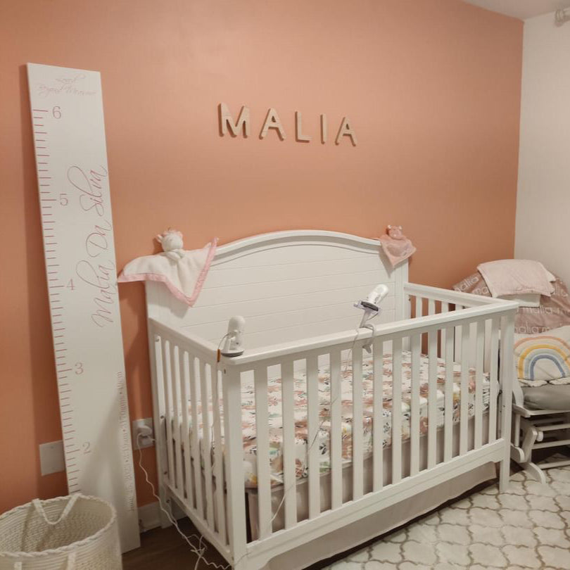 girl nursery with pink walls and a capital name sign