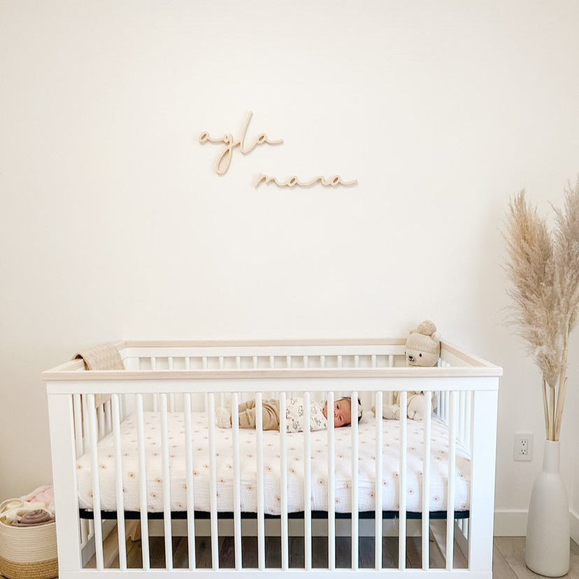 Girl nursery name sign above crib