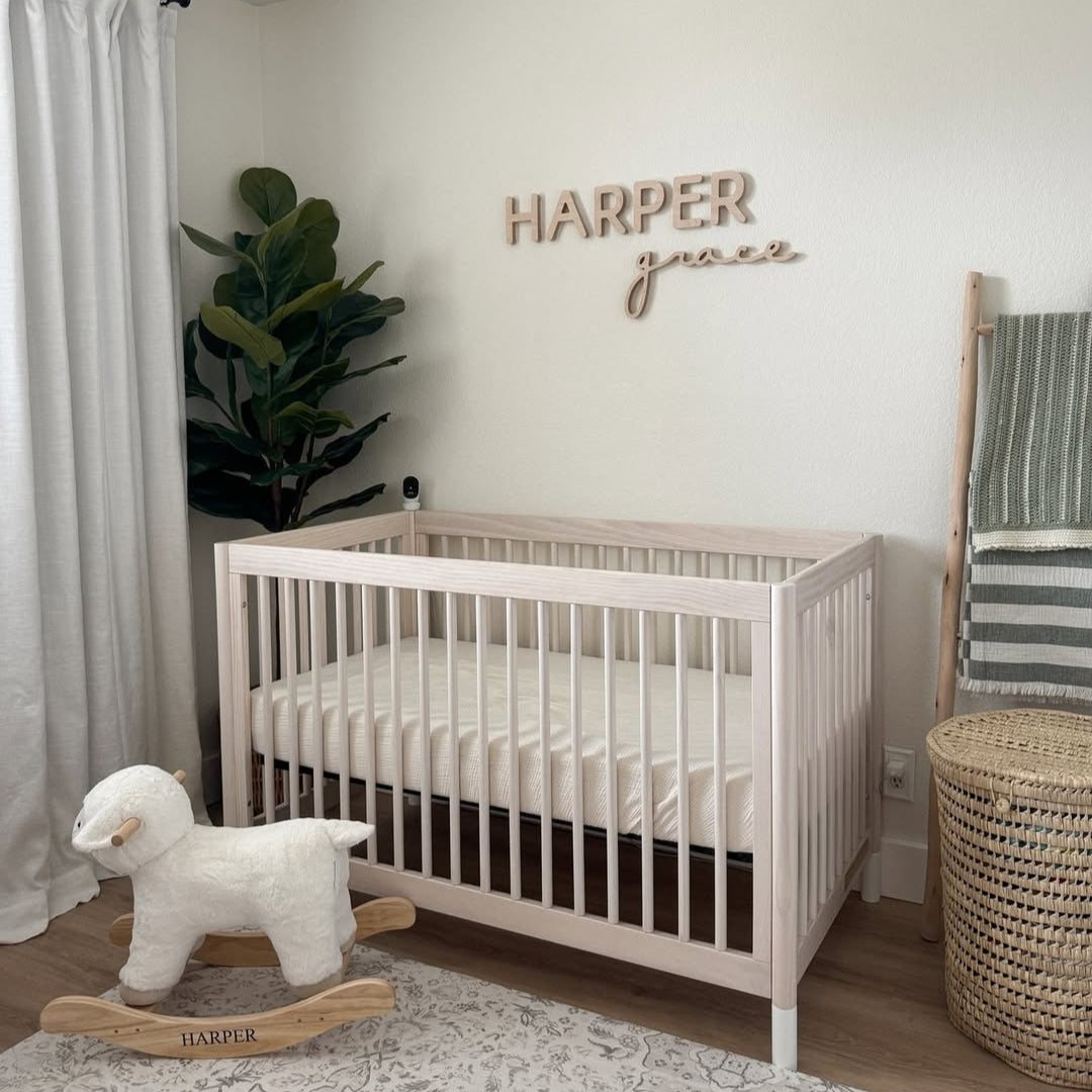 wooden name sign above crib in girl nursery