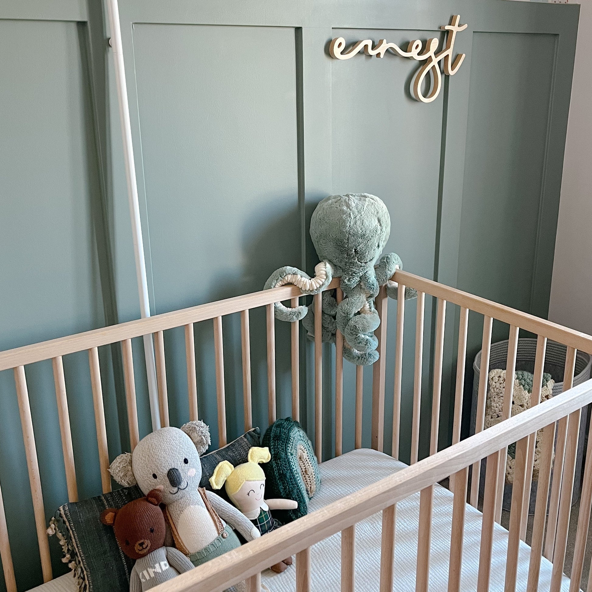 green nursery with green crib sheets and a name sign