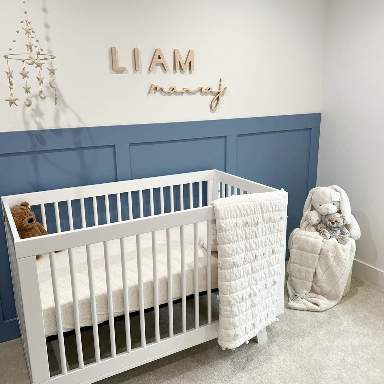 Boy Nursery with blue board and batten half wall with Name Sign above crib