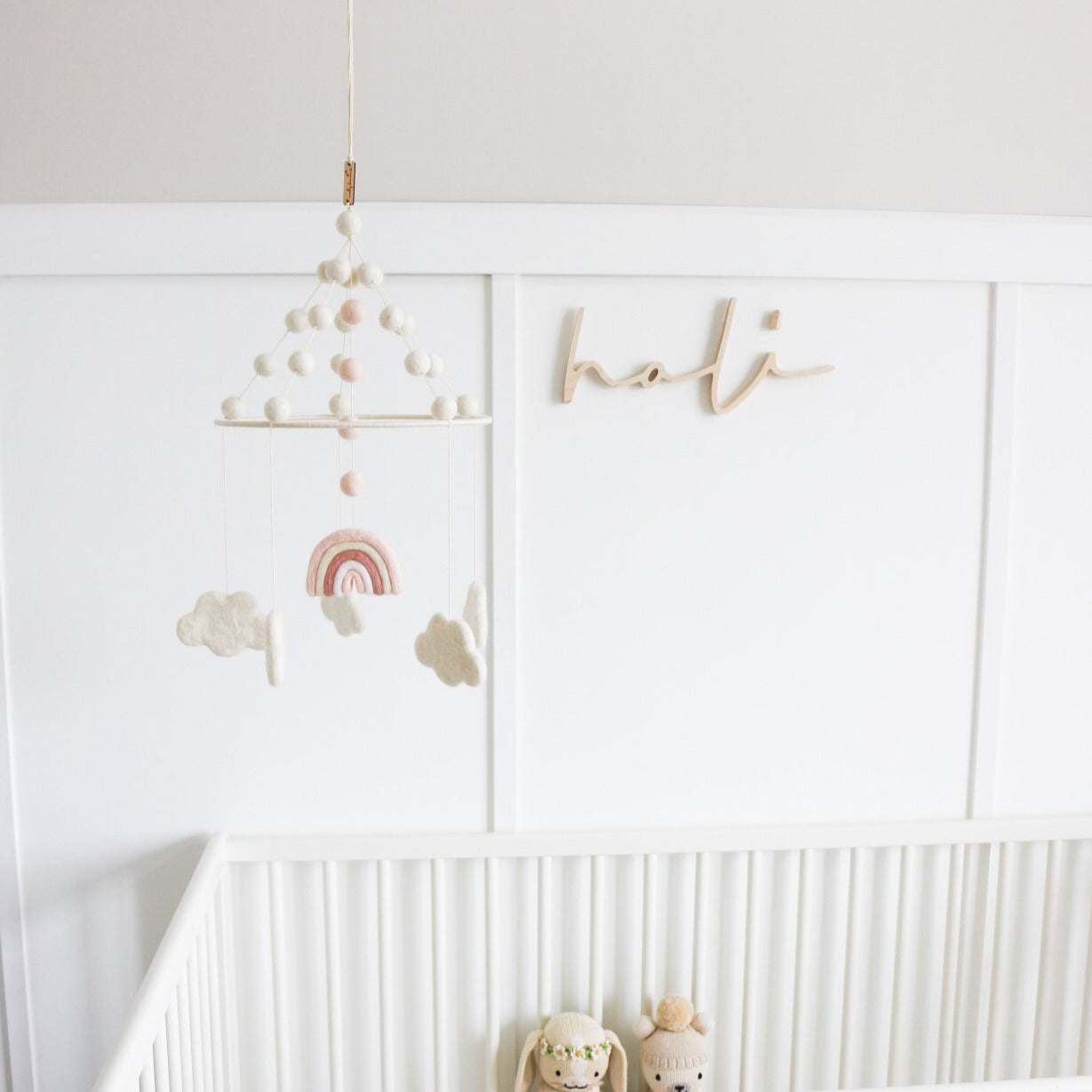 White crib with wooden 'Nursery Name Sign' above it in baby's nursery